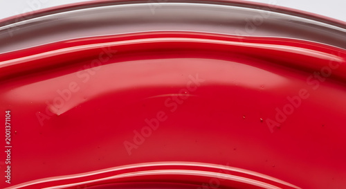 Vibrant red glossy ceramic bowl close up with reflective surface and white background