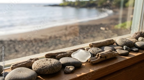 Collection of natural sea glass and smooth stones on a wooden window sill overlooking a beach scene