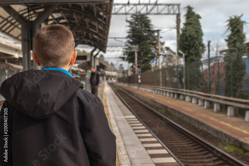 A  little boy standing on the platform and waiting for the train