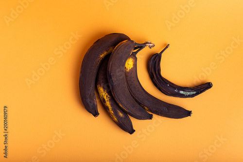 Rotten bananas on an orange background from above. Food waste. Composition with the bananas that can no longer be eaten.