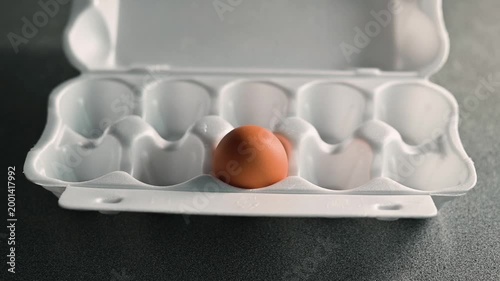 Close-up of person opening tray with one egg