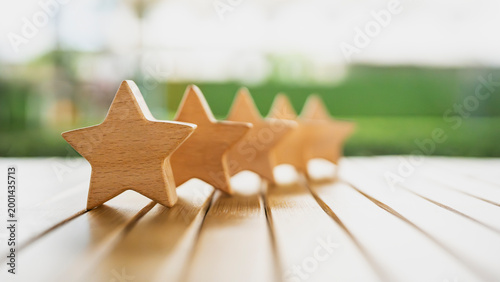 Foto Five wooden stars arranged in a row on a wooden table with blurred green background