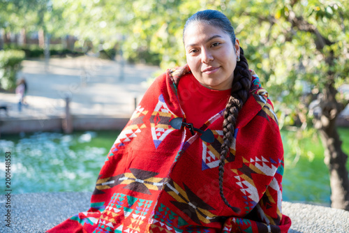 Young indigenous Peruvian woman wearing traditional poncho looking at camera outdoors