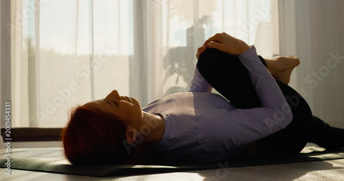 Εκτύπωση καμβά Woman practices stretching and pilates exercises on a mat in her bright living room, embracing a healthy lifestyle