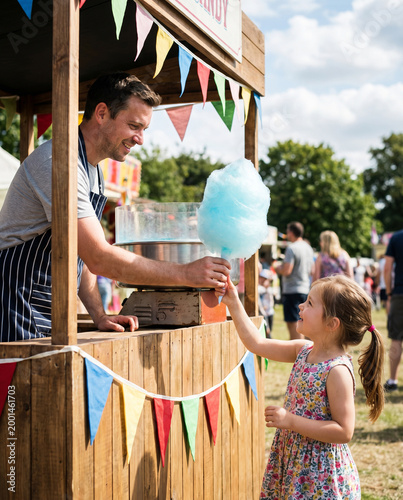 Man Giving Blue Cotton Candy to Young Girl at Fair Stand