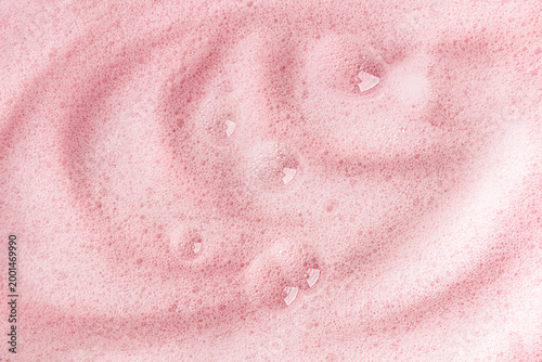 Delicate fluffy soap waves of foam with transparent bubbles on a pink background. A model of a cosmetic product for body skin care. detergent product.