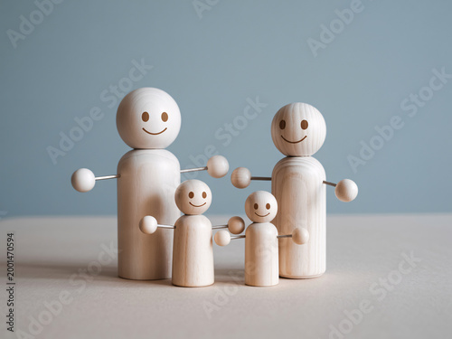 A group of four wooden human figures with smiles on their faces