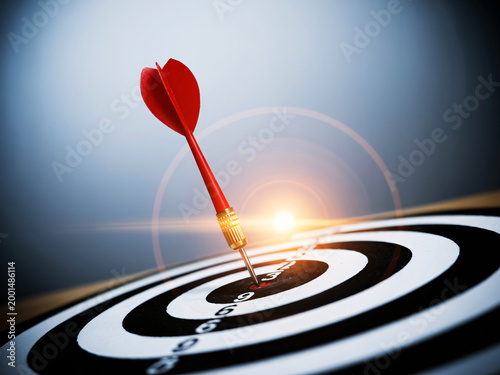 A red dart hits the bullseye on a target with a bright light effect