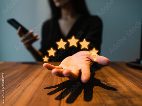 A woman's hand shows glowing stars while she uses her smartphone