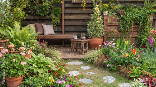 Εκτύπωση καμβά Scenic garden with stone stepping path leading through colorful flower beds and a cozy wooden seating area