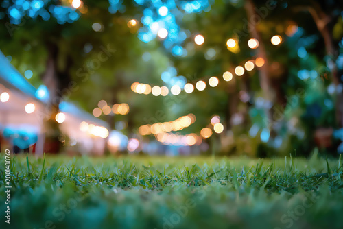 Soft focus on lush green grass with blurred string lights in background