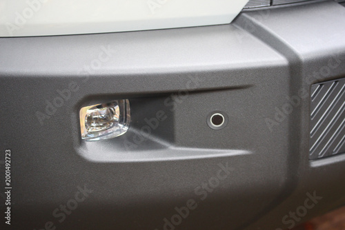 Close up of a new car front bumper with fog light and parking sensor