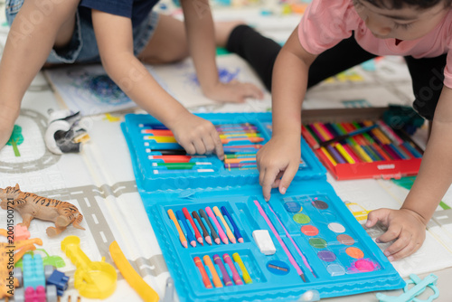 Close up of asian children hands choosing colors from large blue art creative kit