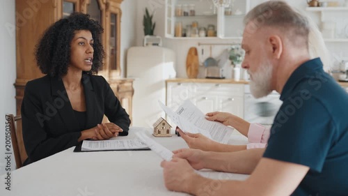 Mature man and woman asking professional real estate agent about credit contract . Mortgage agreement or life and property insurance, buy and sale of house or automobile, credit broker meeting