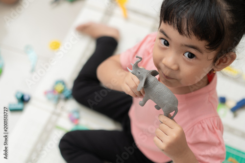 High angle portrait of little Asian girl holding elephant toy looking at camera