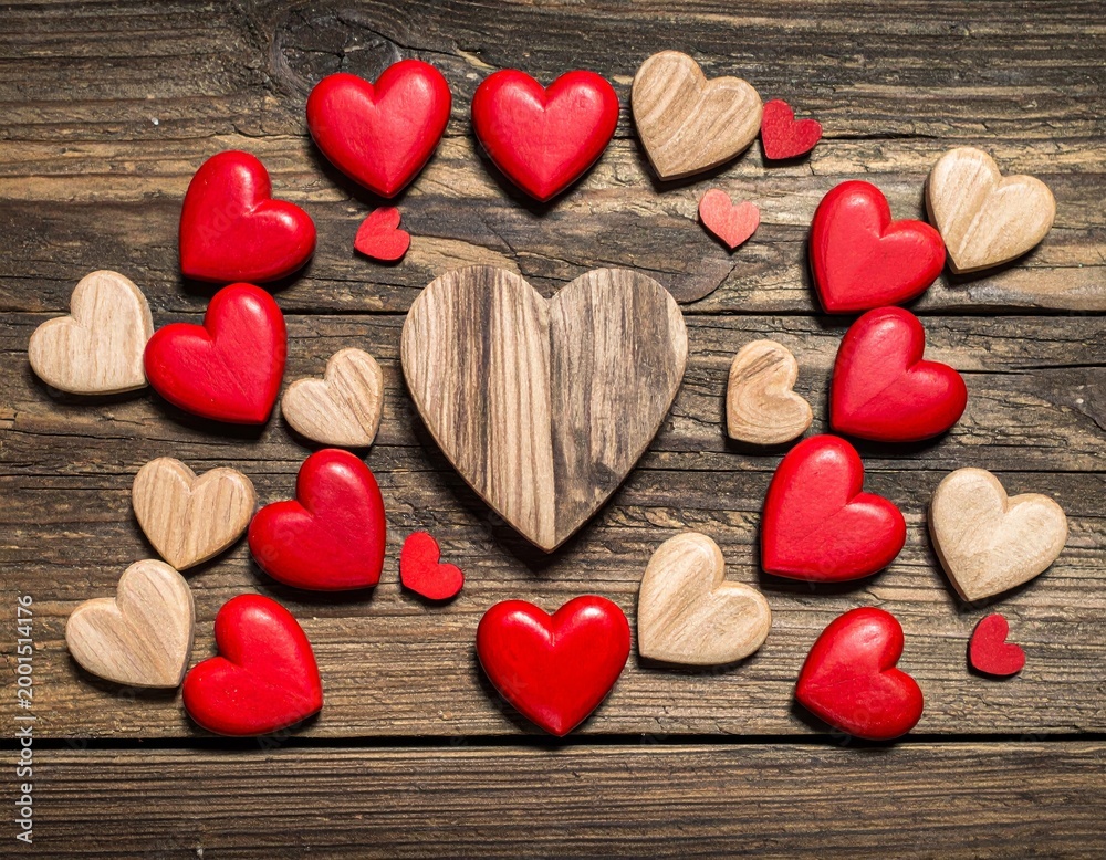 Obraz premium A romantic Valentine's Day decoration featuring red and pink heart symbols on a rustic wooden background with a sweet gift and rose flower for a holiday celebration of love
