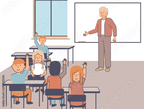 A teacher stands at the front of a classroom with students seated at desks