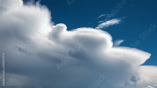 A vibrant blue sky is dramatically punctuated by fluffy, white cumulus clouds, creating a serene and picturesque natural scene.