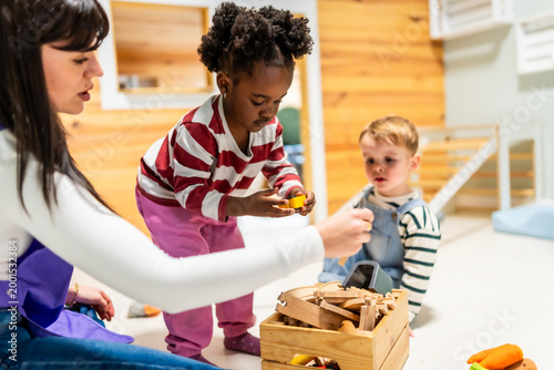 Cuadro en lienzo Daycare teacher playing with diverse children learning toys