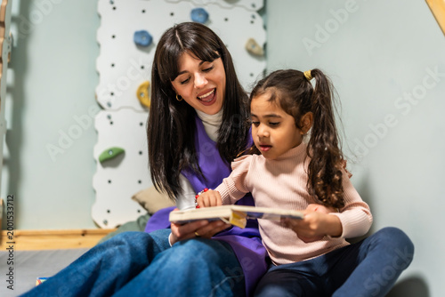 Tableau sur toile Daycare teacher reading book with diverse child