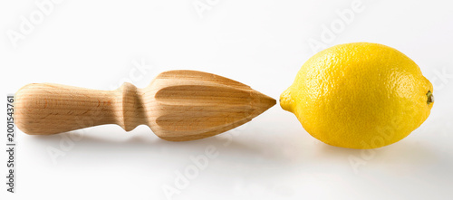 Wooden citrus reamer and whole lemon on white background