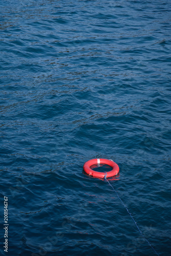 a red lifebuoy floating on the surface of sea water in wind blow and moving wave