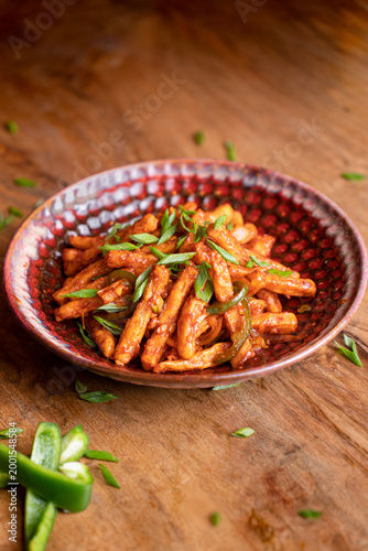 Schilderij op canvas Crispy potato sticks tossed in a spicy, tangy sauce and topped with fresh chopped green onions