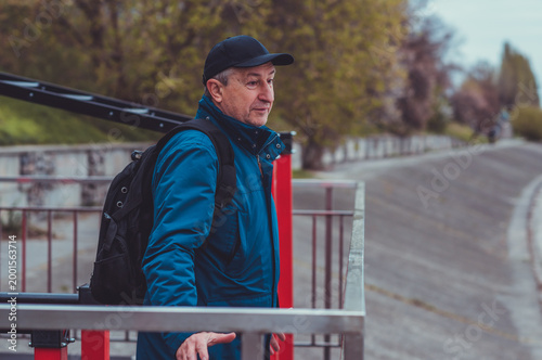 Smiling Senior Man in Blue Jacket and Cap by Riverside. Approachability and Well-being Concept