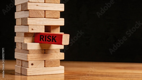 Business risk management concept wooden tower jenga game with red block labeled risk corporate strategy