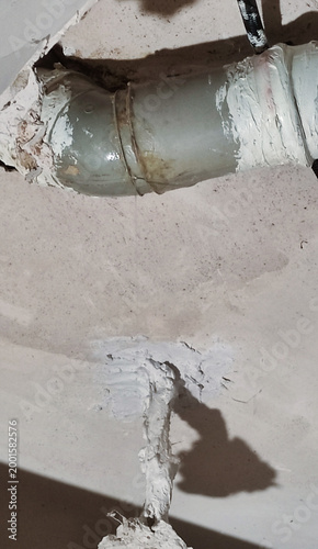 Leaking pipe dripping water from cracked ceiling, causing significant water damage and plumbing issues