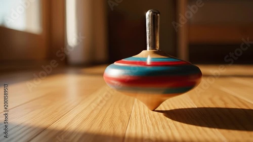 Colorful spinning top on wooden floor in bright indoor sunlight  