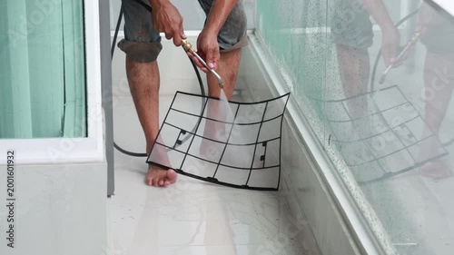 Close-up of a technician using a high-pressure water spray to deep clean air conditioner filters, removing dust and allergens for better air quality.