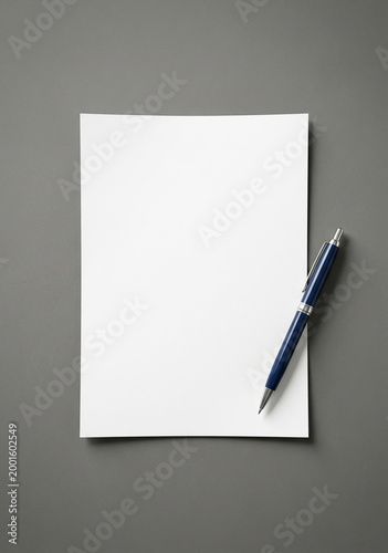 Blank paper and blue pen on gray surface for writing notes or creating documents