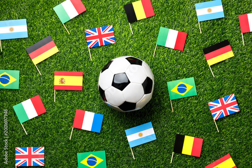 Foto Classic soccer ball surrounded by small flags of different countries on green grass, creating a world cup vibe
