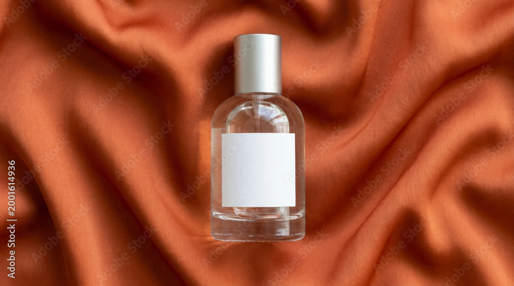 Naklejka premium A perfume bottle sits on a wrinkled brown fabric background.