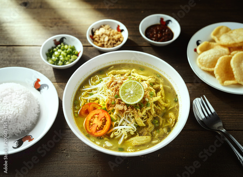 Traditional Indonesian Soto Ayam with Shredded Chicken and Vermicelli. Indonesian Chicken Soup Soto Ayam with Fresh Toppings and Side Dishes
