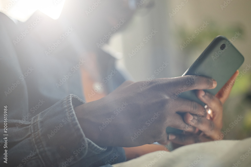 Fototapeta premium Close up of Black young adult man using smartphone for mobile messaging and online browsing. Suitable for social media, fintech, app promotion, digital communication campaigns