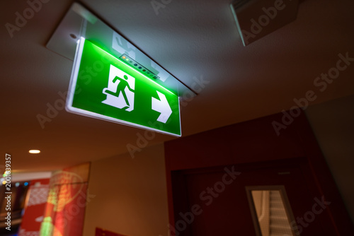 Quadro su tela An emergency fire exit light box with arrow hangs from a hospital ceiling, combining evacuation drill concept with clear safety direction and escape guidance