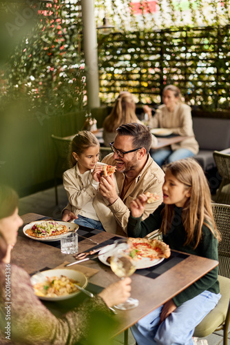 Happy Family Eating Pizza Together At Outdoor Restaurant Patio During Casual Weekend Lunch