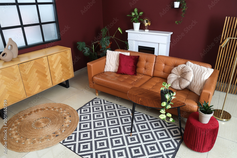 Fototapeta premium Interior of modern living room with cozy brown sofa, coffee table, ottoman and fireplace