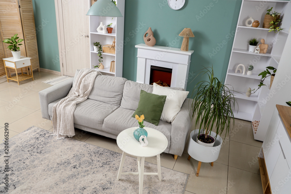 Fototapeta premium Interior of stylish living room with grey sofa, shelf units and plants