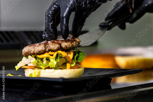 Chef preparing gourmet burger with fresh ingredients for restaurant menu