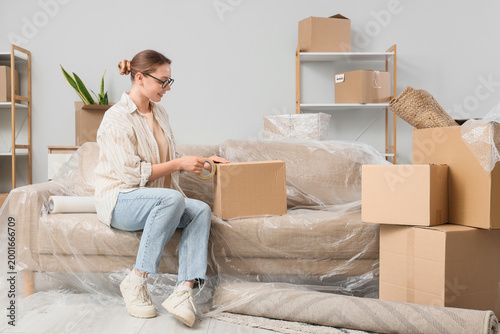 Young woman taping box in r...