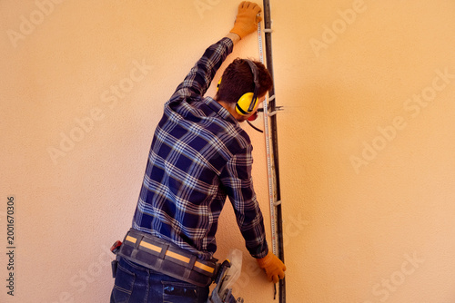 Electrician wearing ear protection marks and measures before electrical wiring installation in indoor construction site
