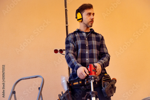 Worker performs precise marking with laser level preparing wall chases for electrical cable installation in construction site