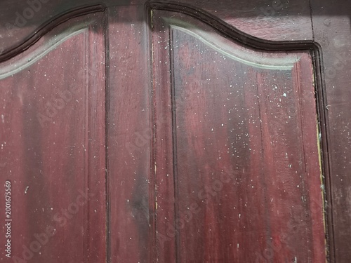 Close-up of an old, weathered wooden door with peeling paint and intricate carvings, showcasing rustic texture and vintage charm.