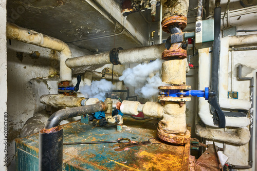 Old boiler room pipes leaking steam
