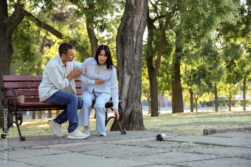 Young man with his wife having heart attack on bench in park
