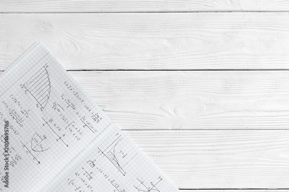 Fototapeta premium Copybook with handwritten maths formulas on white wooden background