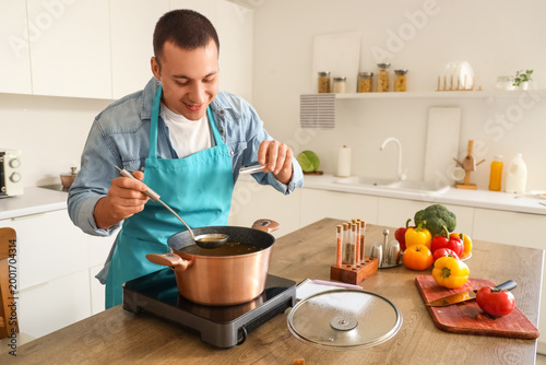 Young man peppering soup in...